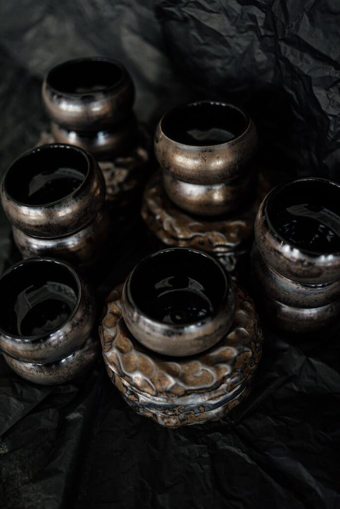 Stylish handmade ceramic pots with a dark, artistic finish on a crumpled background, perfect for decor.