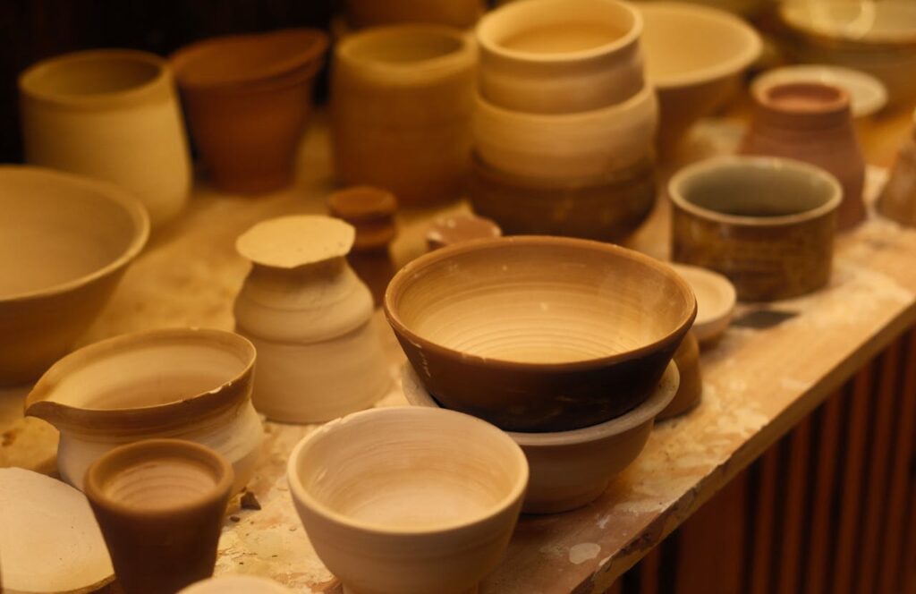 A collection of handcrafted ceramic bowls displayed in an artisan pottery studio with soft lighting.