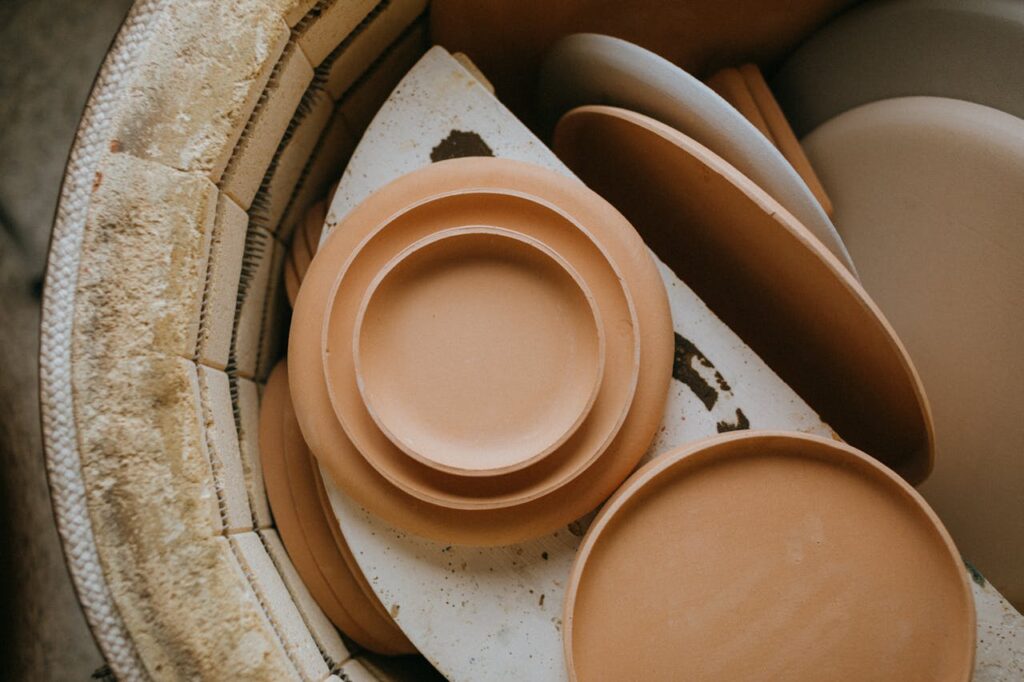 Warm-toned ceramic plates stacked inside a kiln, ready for firing.
